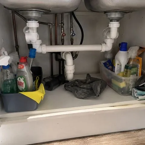 The pipes and cleaning bottles in the cupboard under the sink